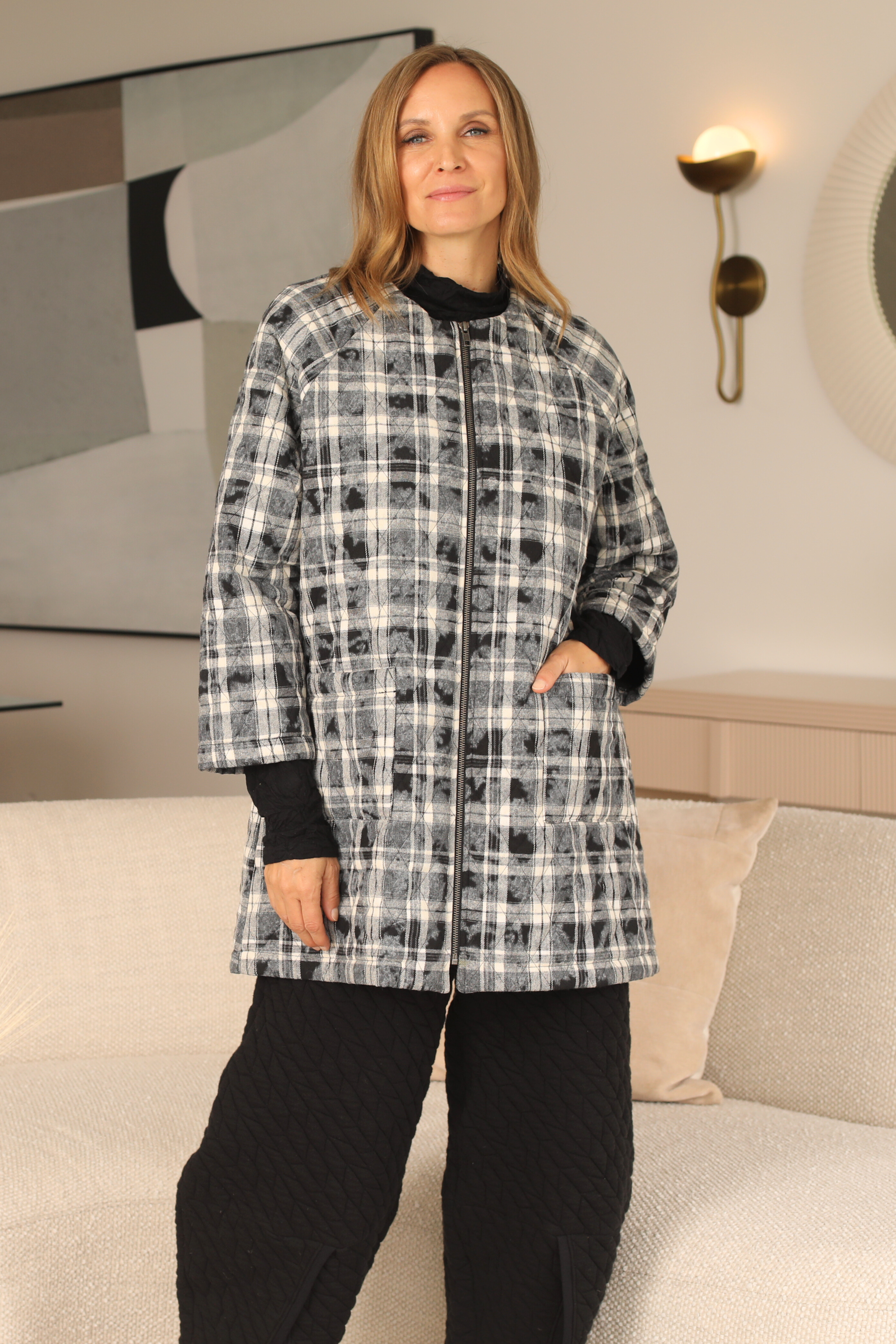 Woman wearing a plaid coat in a living room setting