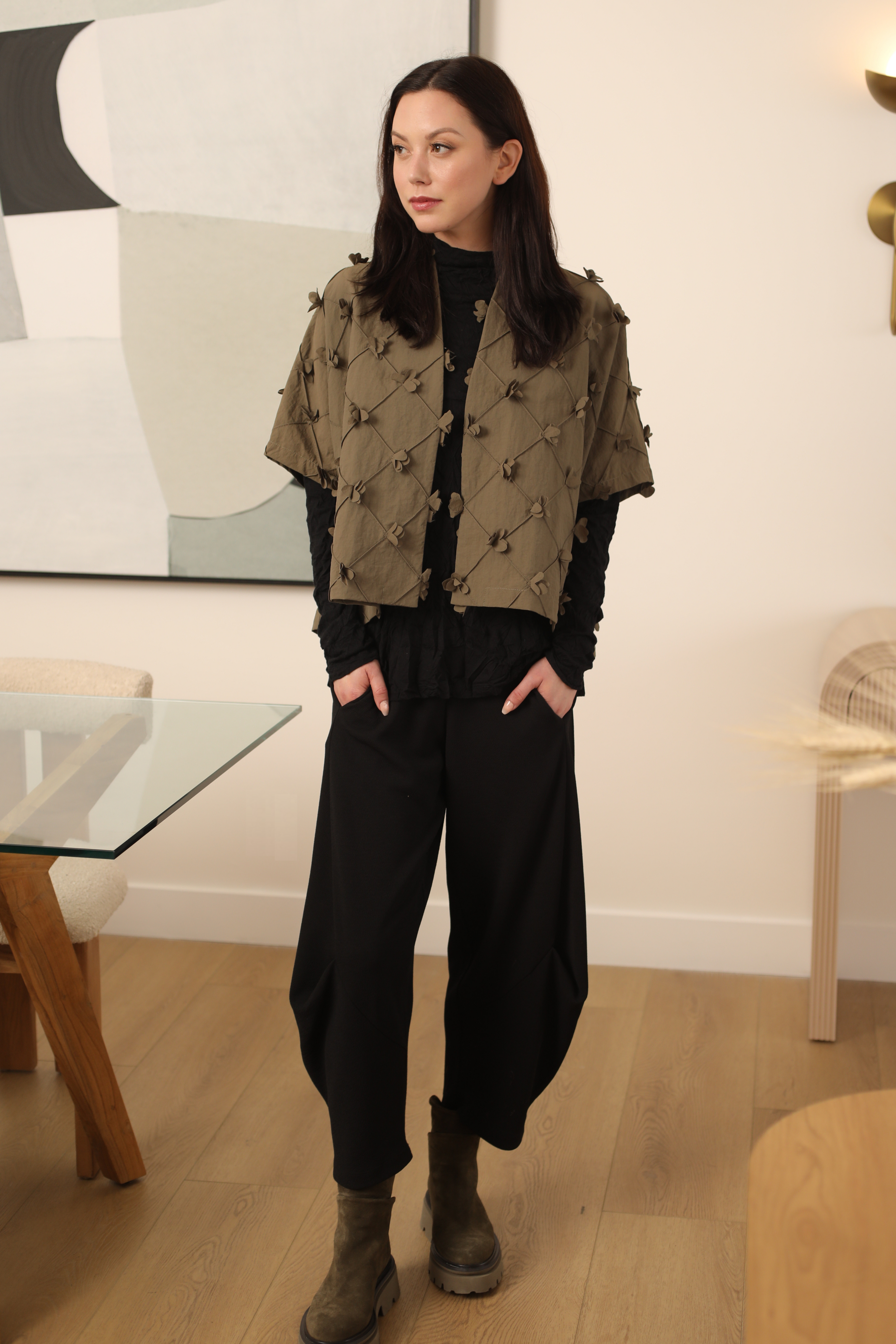 Woman wearing a patterned jacket and black pants in an indoor setting